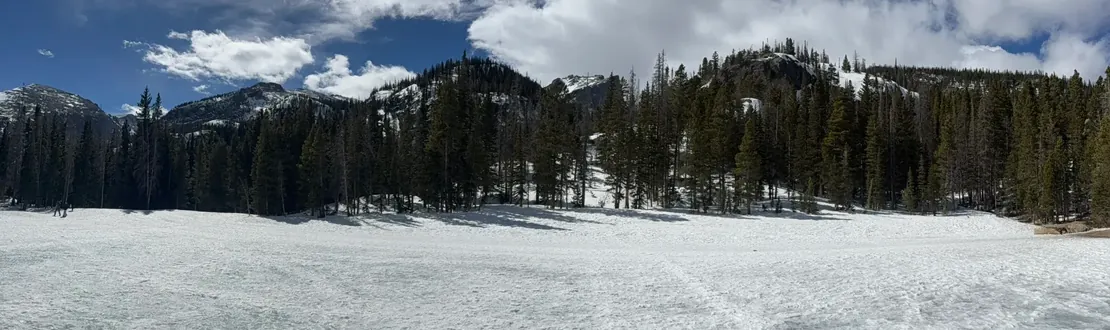 Snow-covered frozen Bear Lake under a bright winter sky, dark pines along the far shore
