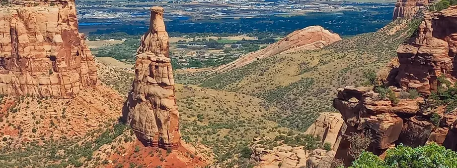 Independence Monument rising from a red rock canyon, the Grand Valley stretching out beyond