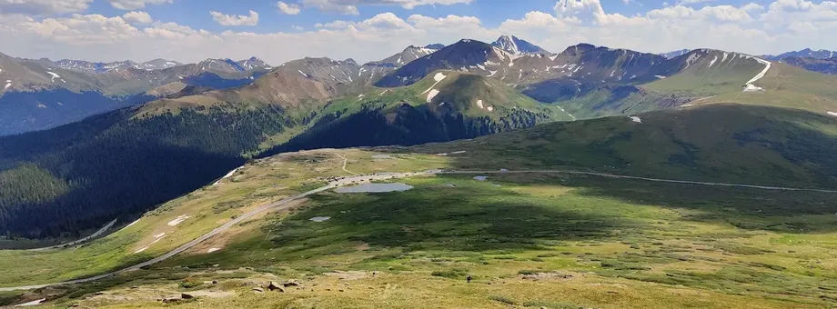 Green alpine tundra near Independence Pass with rows of mountains and scattered snow beyond