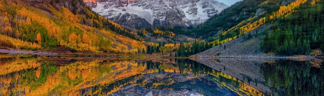 Maroon Bells reflected in Maroon Lake, aspens turning gold on the slopes