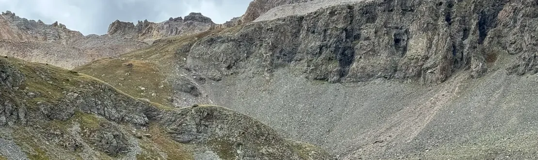 Yankee Boy Basin with grey cliffs above a green valley and a small waterfall