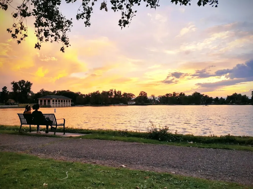 Sunset over Smith Lake at Washington Park in Denver, with the boathouse lit by string lights across the water